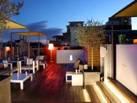 a rooftop deck with chairs and tables on a building at Axel Hotel Barcelona - Adults Only in Barcelona