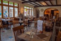 ein Restaurant mit Holztischen und -stühlen und Fenstern in der Unterkunft Logis Hôtel Au Gai Soleil du Mont-Aiguille in Chichilianne