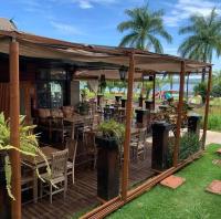 eine Holzterrasse mit Stühlen, Tischen und einem Pavillon in der Unterkunft Apartamento Life Resort Brasília in Brasilia