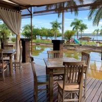 eine Holzterrasse mit einem Tisch, Stühlen und Wasser in der Unterkunft Apartamento Life Resort Brasília in Brasilia