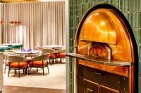 a restaurant with a pizza oven in the middle of a room at Holiday Inn Manchester Airport T2 by IHG in Hale