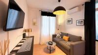 a living room with a couch and a flat screen tv at Studio Casa Aelys - Quartier des Arènes - Béziers in Béziers