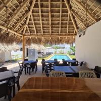 Un restaurante con mesas y sillas y una piscina. en BUNGALOWS COLIBRI, en Las Galeras