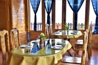 una sala da pranzo con due tavoli, sedie e finestre di Hmong Eco Villas a Sa Pa