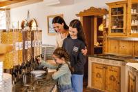 a woman and two children standing in a kitchen with wine bottles at Familotel Kindl in Neustift im Stubaital