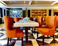 een eetkamer met een witte tafel en oranje stoelen bij The Mars Resorts in Meerut