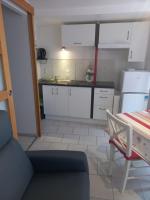 une petite cuisine avec des placards blancs et une table dans l&#39;établissement SNTL, à Jonzac