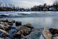 a river with rocks and a bridge in the background at Hotel Anker in Saalfeld