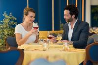 a man and woman sitting at a table drinking wine at Hotel Luna in Bibione