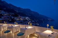 a group of tables on a balcony with a view of a city at Hotel Conca d'Oro in Positano