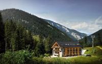 a house on the side of a hill with a mountain at Apartmany Demänovka in Demanovska Dolina