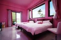 a pink bedroom with two beds and two windows at Xinyue B&amp;B in Fenglin