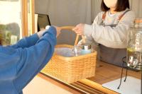 Una mujer sostiene una canasta sobre una mesa. en てんとうみ 渋川海岸グランピング Tentoumi Shibukawa Beach Glamping, en Tamano