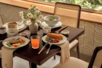 uma mesa com pratos de comida e bebidas sobre ela em RUBENS BOUTIQUE HOTEL em Phan Thiet