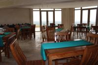 restauracja z drewnianymi stołami i krzesłami oraz oknami w obiekcie Bhalil Farm House w mieście Sefrou