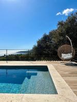 a swimming pool with a chair and a swing at Villas de standing avec magnifique vue mer et piscines privées, Sagone in Sagone