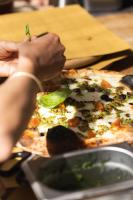una persona sosteniendo una porción de pizza en una mesa en LEGASEA - Cascais Guesthouse, en Cascais