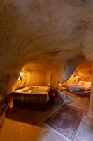 a room with a tub in a cave with two beds at feris cave hotel in Urgup