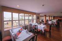 a dining room with white tables and chairs and windows at Victoria Chau Doc Hotel in Chau Doc