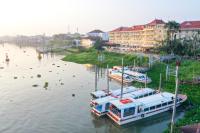 a group of boats docked on a river with buildings at Victoria Chau Doc Hotel in Chau Doc