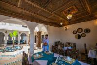 a man standing in the middle of a room with tables at Riad Jouba in Merzouga