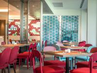 Un restaurante con mesas de madera y sillas rojas. en Ibis Styles Phuket City, en Phuket