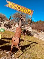 a wooden person with a sign in the grass at Le Planzollais in Planzolles