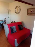 a red couch in a room with a clock on the wall at Gîte Chez Dado &amp; Denis Saint Martin d&#39;Ardèche in Saint-Martin-dʼArdèche