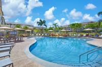 Una piscina en un resort con sillas y sombrillas. en Residence Inn by Marriott Oahu Kapolei, en Kapolei