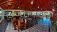 a restaurant with a large wooden table and chairs at Chateau Arenal Hotel & Restaurante in El Castillo de La Fortuna