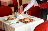 a person cutting a plate of food on a table at Nafron Hotel in Prizren