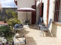 a patio with an umbrella and a grill and chairs at Bompastor in Bompas