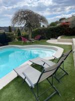 a pool with two chairs and a table next to it at Gîte des Restanques in Grasse