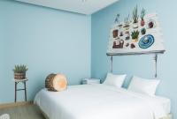 a bedroom with a white bed and a blue wall at Beat Hotel Bangkok in Bangkok