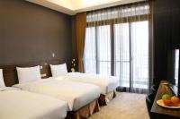 a hotel room with three beds and a window at Capital Hotel SongShan in Taipei