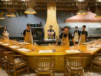 チェンライにあるパ　サック　トンのキッチンの大きなテーブルの周りに立っているシェフのグループ