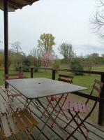 a picnic table and chairs on a deck with a field at CAMPING DE LA CHALARONNE in Saint-Didier-sur-Chalaronne