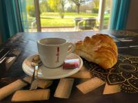 a cup of coffee and a croissant on a table at CAMPING DE LA CHALARONNE in Saint-Didier-sur-Chalaronne
