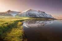a mountain reflecting in a body of water at Fisherman Guesthouse Flateyri in Flateyri