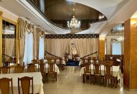 een restaurant met tafels en stoelen en een kroonluchter bij Готель МАГНАТ in Sutysky