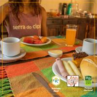 a woman sitting at a table with a plate of food at POUSADA VILA ACONCHEGO- Sossego- Em Meio Há Mata Nativa- by MARCOS MICOZZI in Serra do Cipo