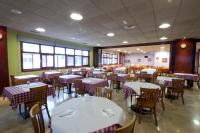 una sala da pranzo con tavoli e sedie bianchi con tavoli e sediesktop di Hotel Torques a La Coruña