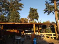 Un pabellón de madera con mesas, sillas y árboles. en Beach house à Marina di Sorbo …Corse, en Sorbo-Ocagnano