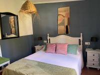 a bedroom with a bed with pink and green pillows at Molino El Mastral in Tarifa