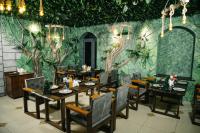 un restaurante con mesas y sillas y una pared con plantas en Asmald Palace Hotel, en Qo‘qon