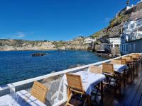 Una fila de mesas y sillas en un balcón con vista al agua. en Roccobarocco Boutique Hotel, en Isquia