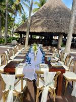 a long dining table with chairs and a straw umbrella at HOTEL TESORO BEACH in San Luis La Herradura