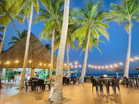 a restaurant on the beach with palm trees at HOTEL TESORO BEACH in San Luis La Herradura