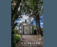 ein großes Steinhaus mit Bäumen davor in der Unterkunft Taldraeth - Old Vicarage Guest House in Penrhyndeudreath