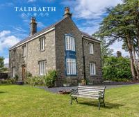 ein Gebäude mit einer Bank davor in der Unterkunft Taldraeth - Old Vicarage Guest House in Penrhyndeudreath